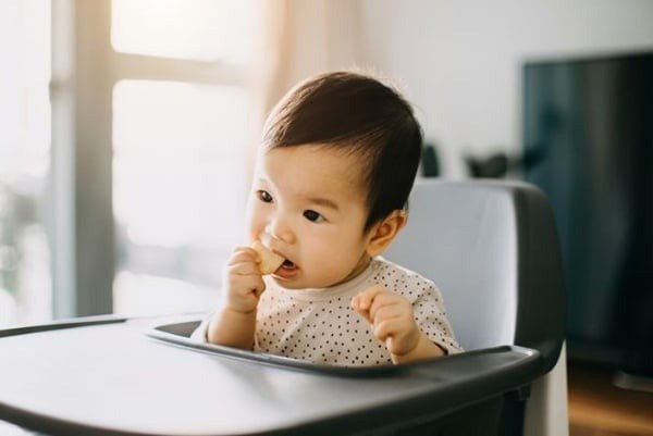 Bánh gạo An cho bé mấy tuổi nên dùng, hình ảnh bé đang tự ăn bánh gạo An rất vui vẻ