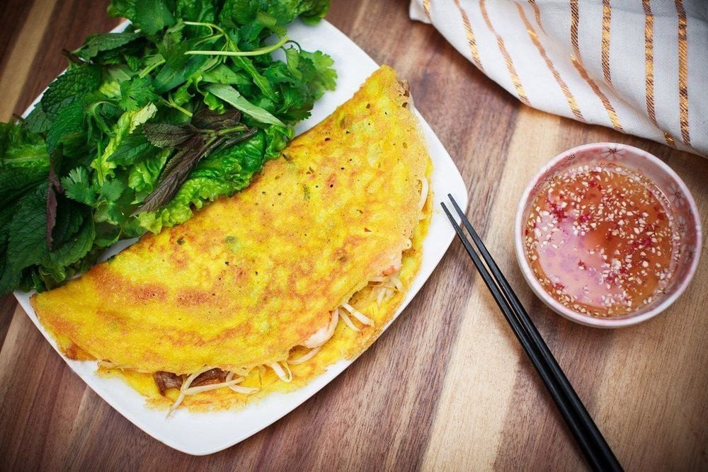 Chảo bánh xèo đang được tráng với lớp vỏ mỏng vàng ươm.