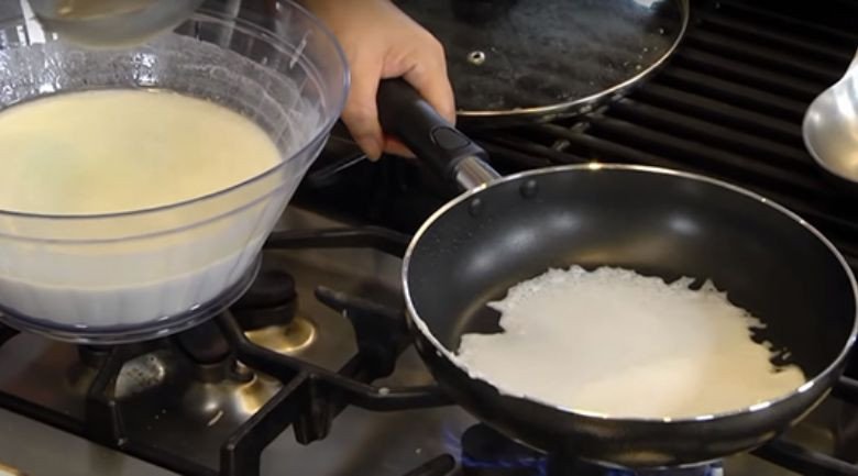 Tráng vỏ bánh cuốn từ bột gạo trên chảo nóng một cách khéo léo
